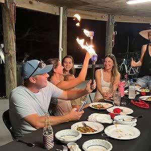 Guests holding flaming torches at an evening hibachi dinner in Miramar Beach