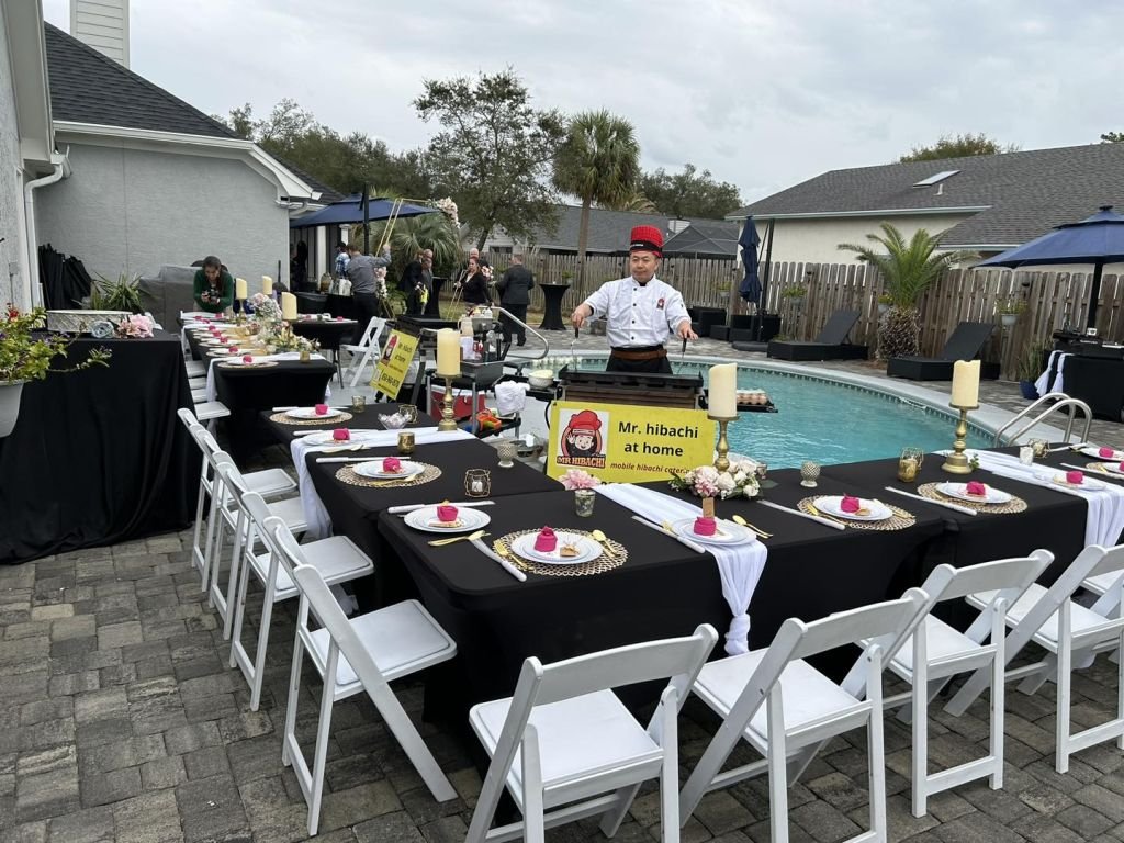 Poolside tables with black linens set for a hibachi dinner