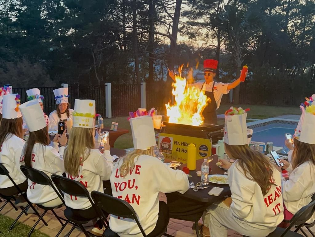 Bachelorette guests in chef hats watching a hibachi flame show