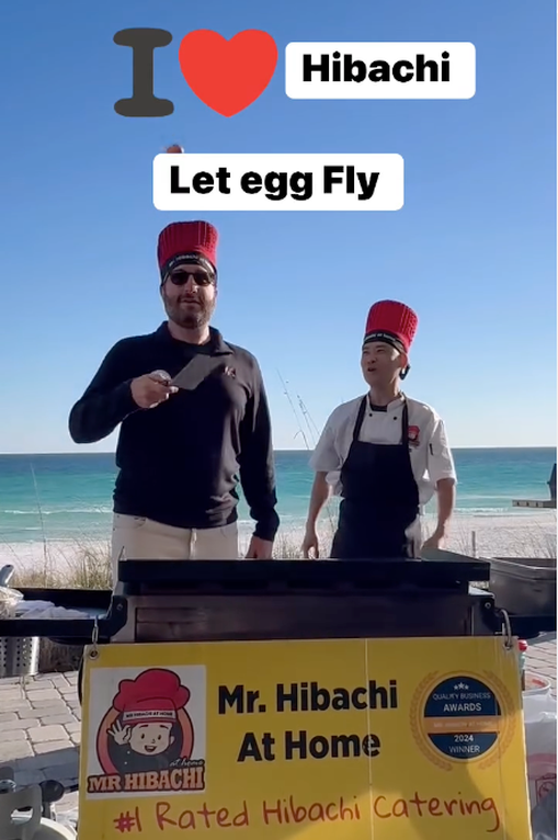 Two hibachi chefs at a mobile grill on the beach