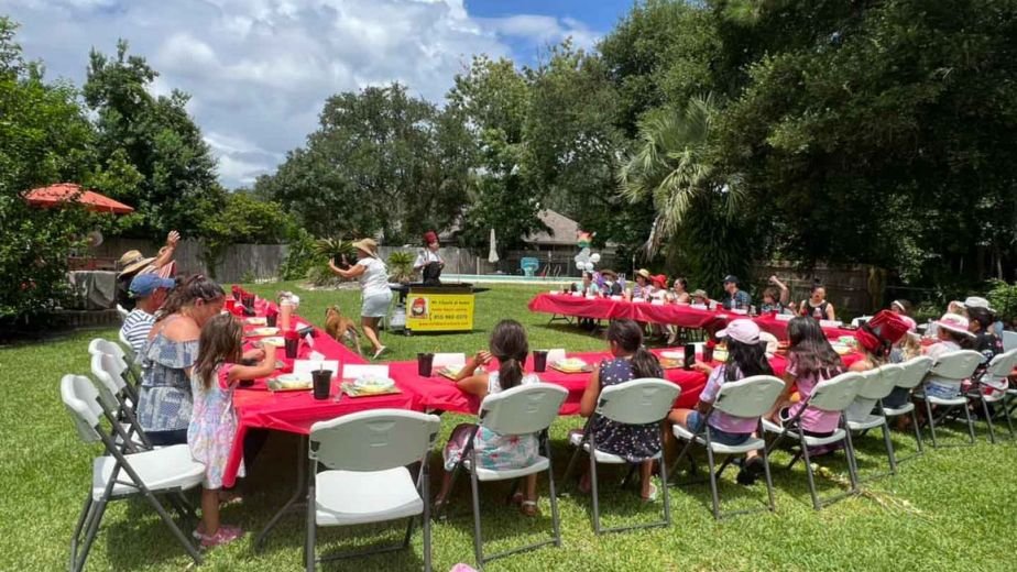 Large backyard hibachi party with red tablecloths
