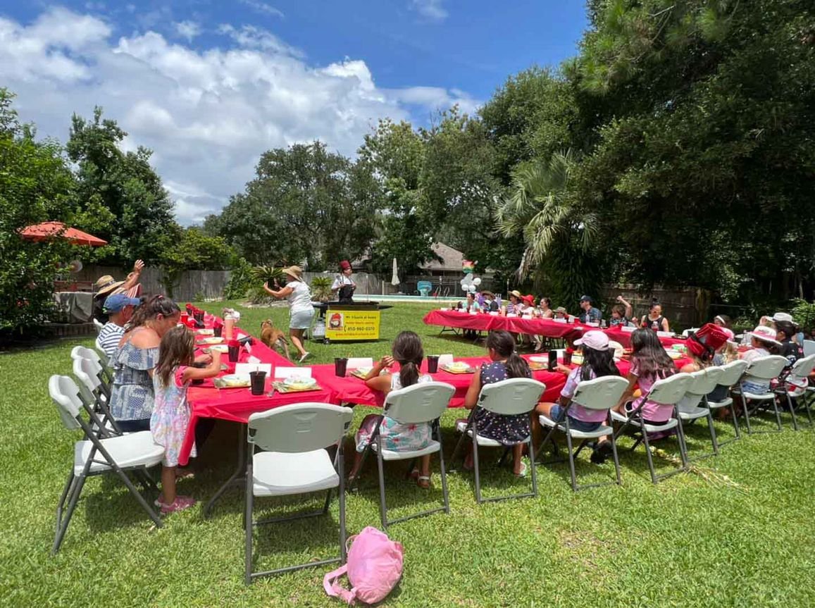 Large backyard hibachi party with red tablecloths