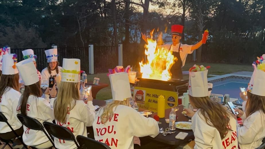 Bachelorette guests in chef hats watching a hibachi flame show
