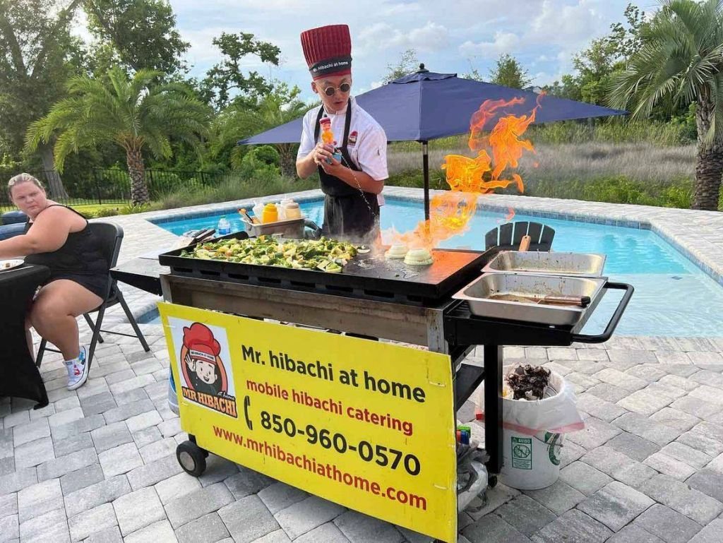 Hibachi chef cooking with flames at a poolside grill cart