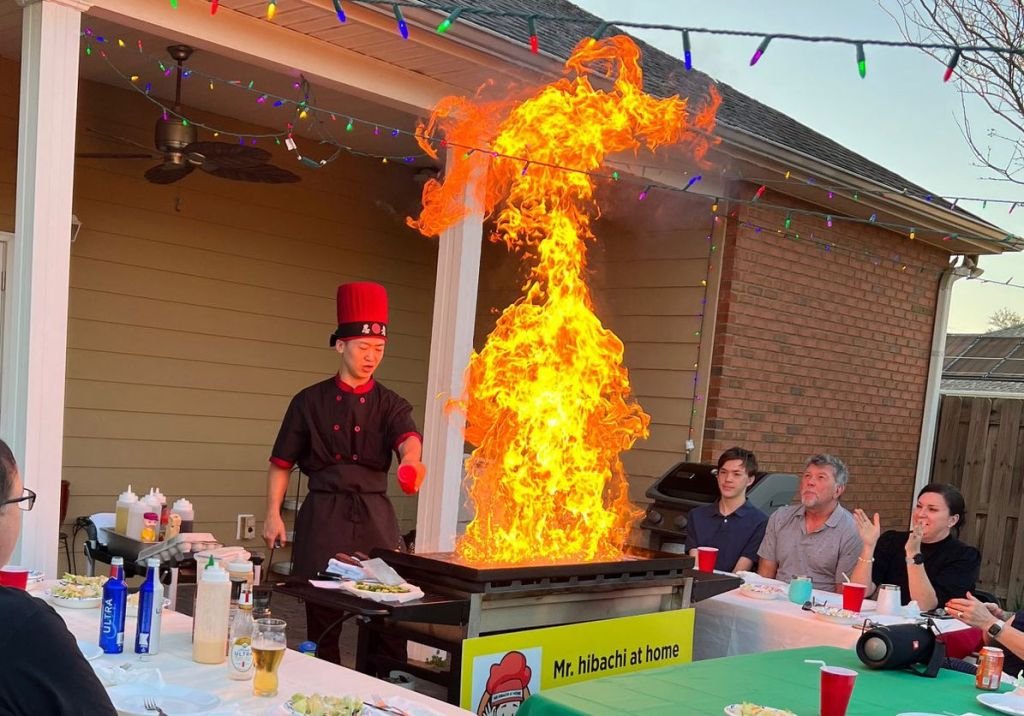 Hibachi chef with a tall flame on a covered patio