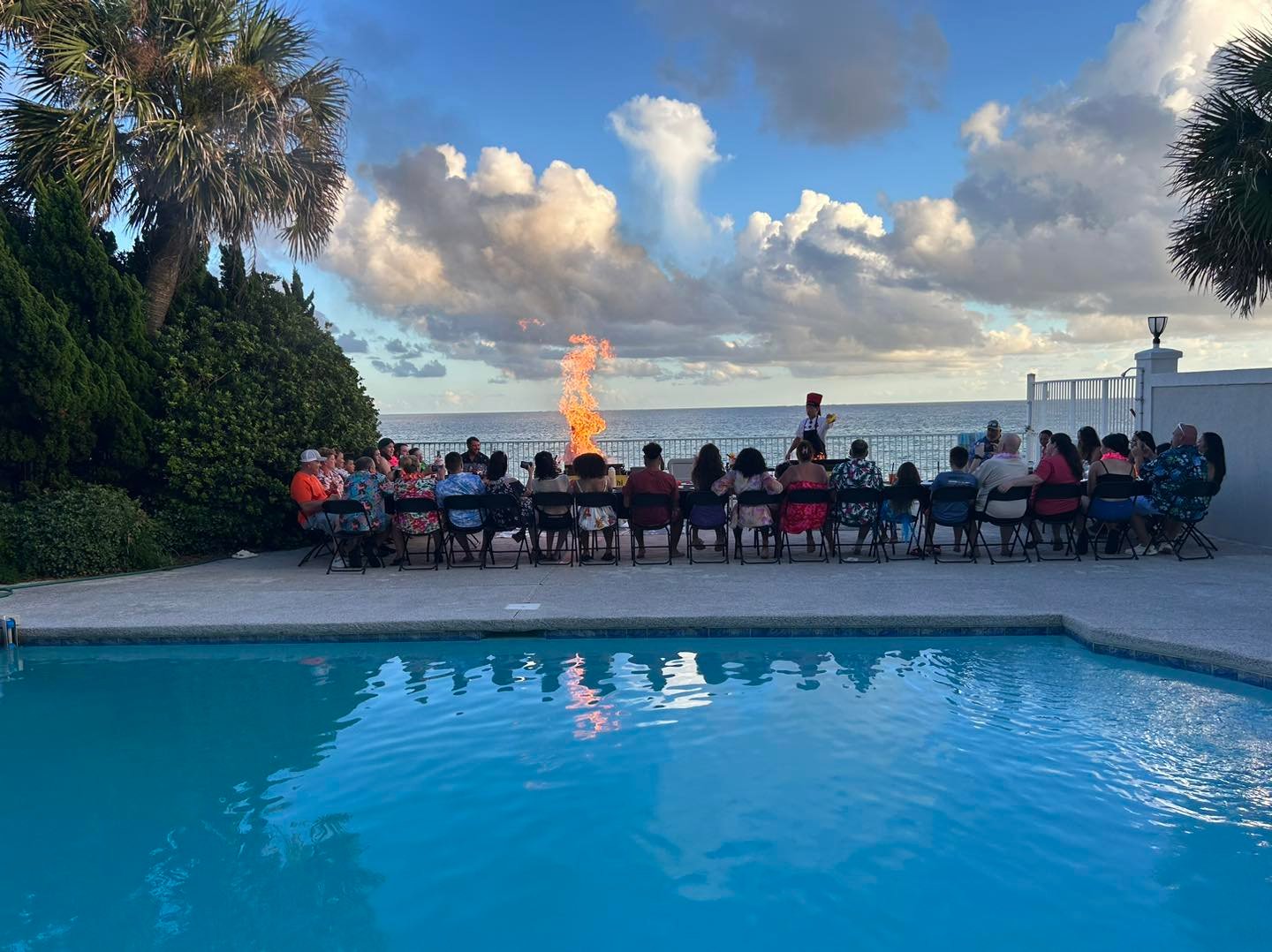 Guests seated by a pool at sunset for a hibachi dinner