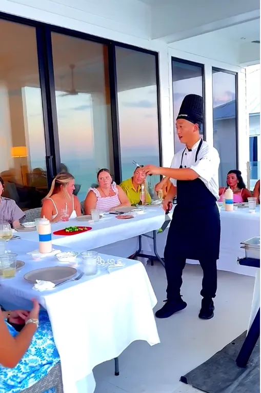 Hibachi chef serving a group in a bright room with an ocean view