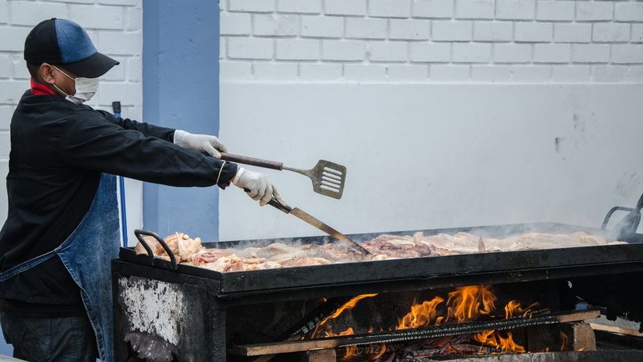 Cook grilling meat over an open-flame grill
